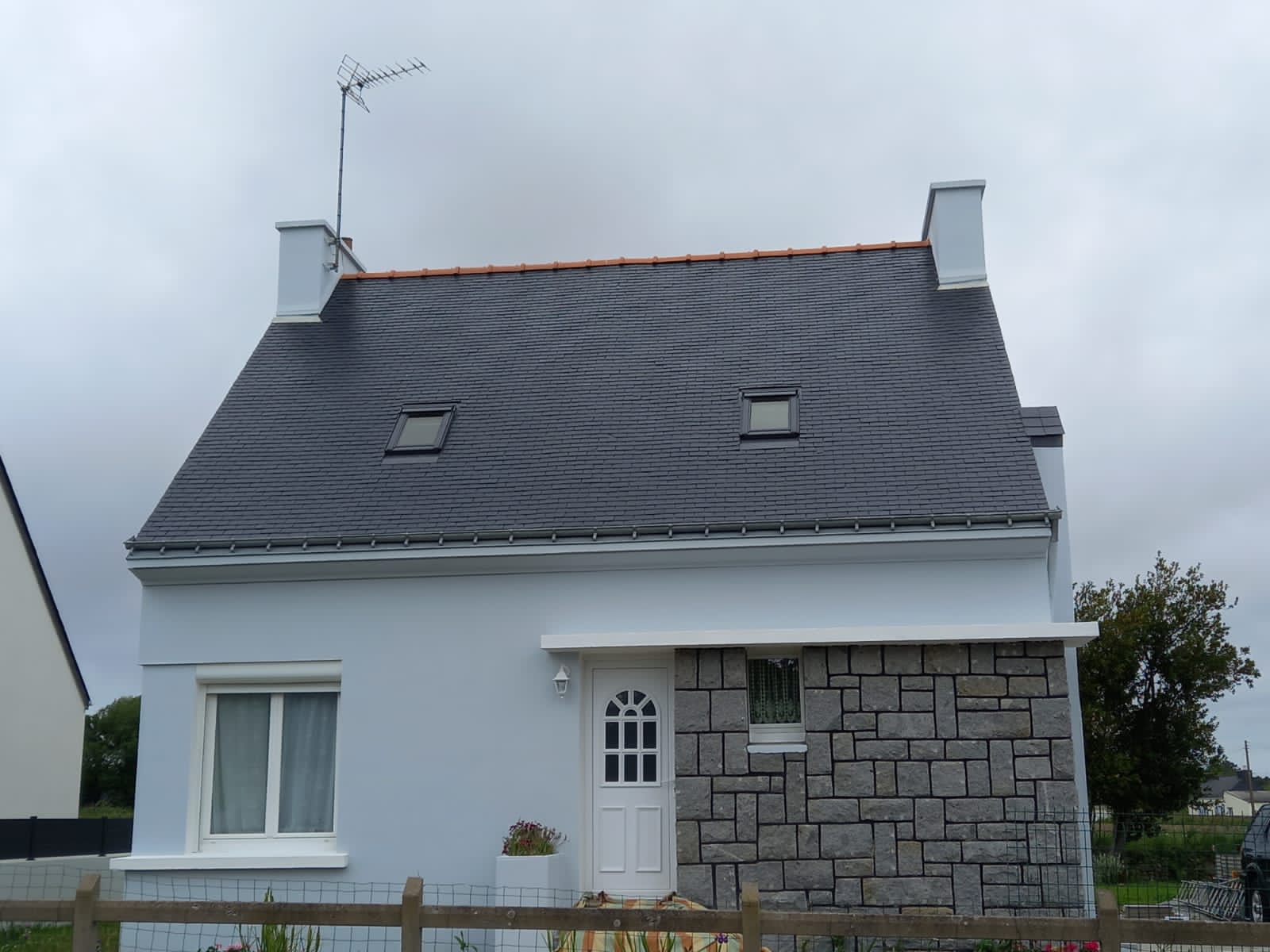 Toiture en ardoise rénovée sur maison bretonne avec soubassement en pierre